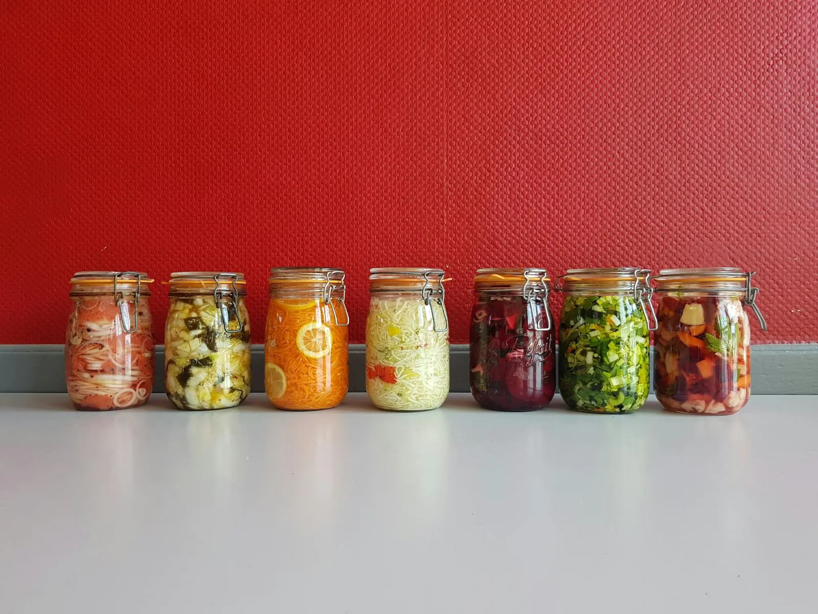 Una fila de tarros con verduras fermentadas de colores