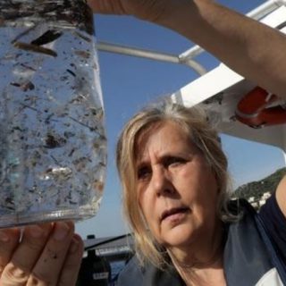 bote cristal con agua y multitud plásticos flotando en ella